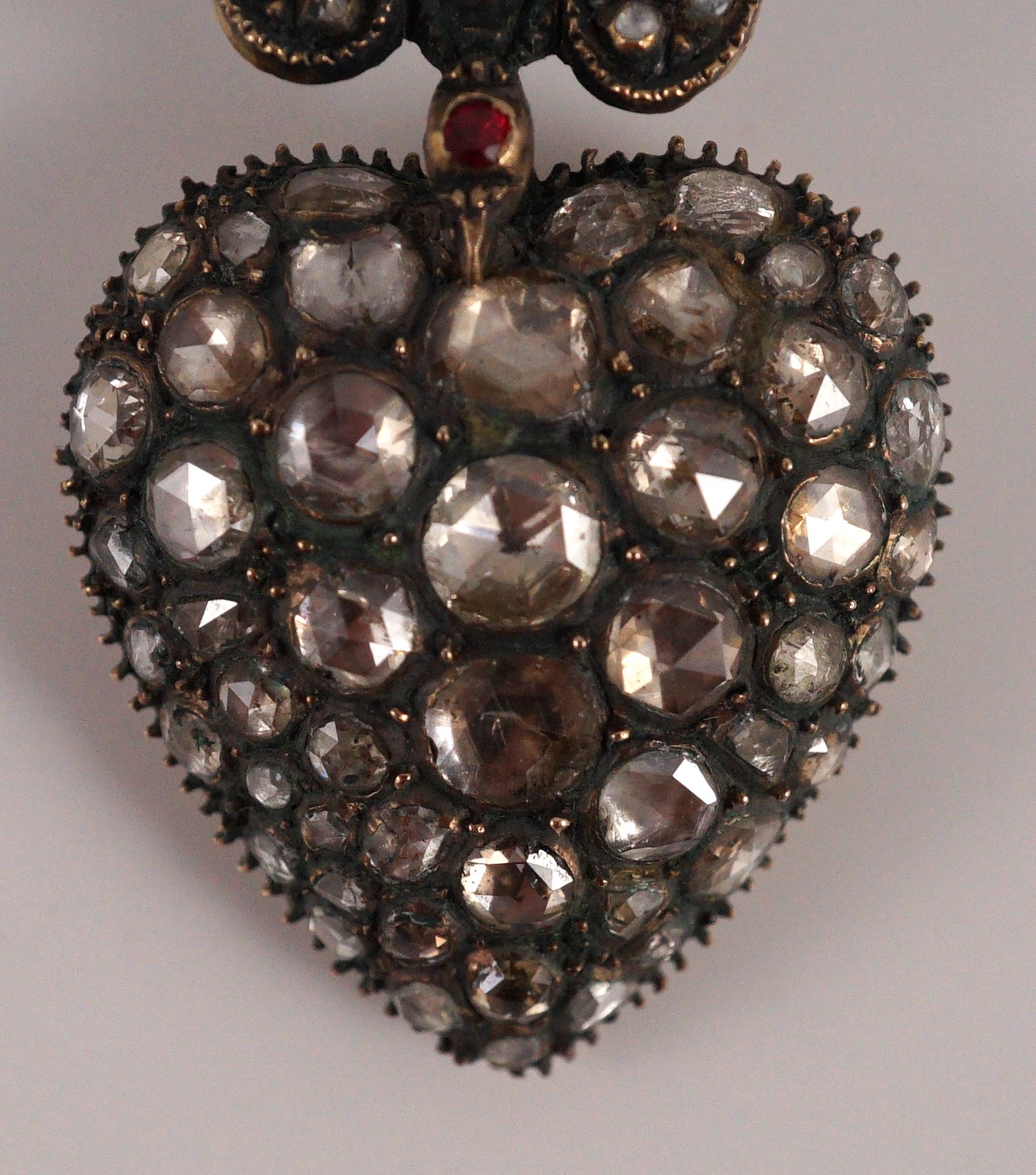 A Victorian style gold and graduated rose cut diamond set heart shaped pendant, with diamond and spinel? set bale modelled as a swallow